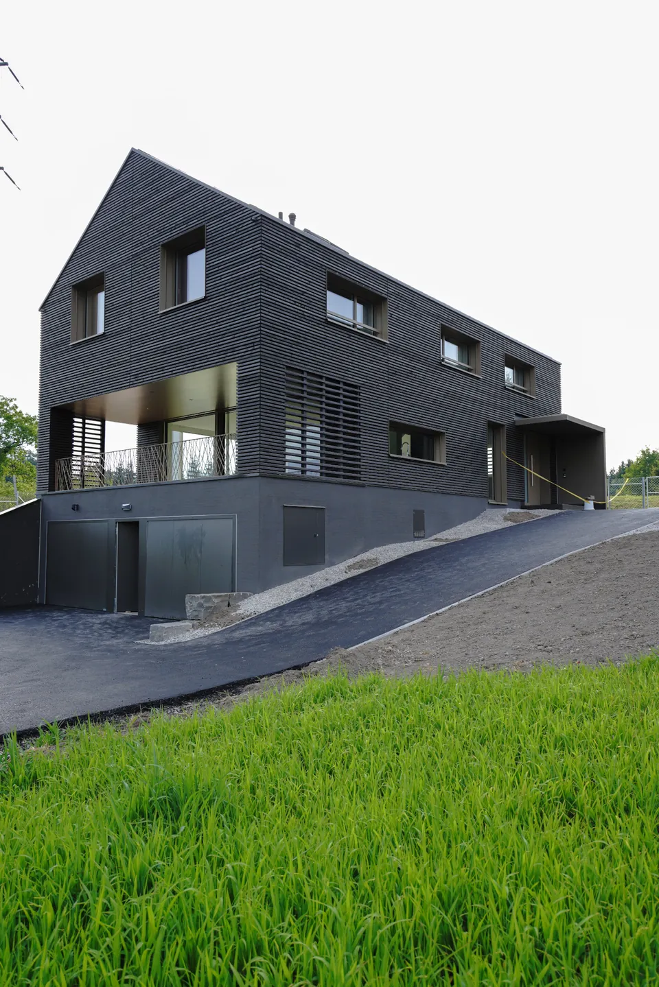 Neubau mit dunkler Holzfassade am Hang