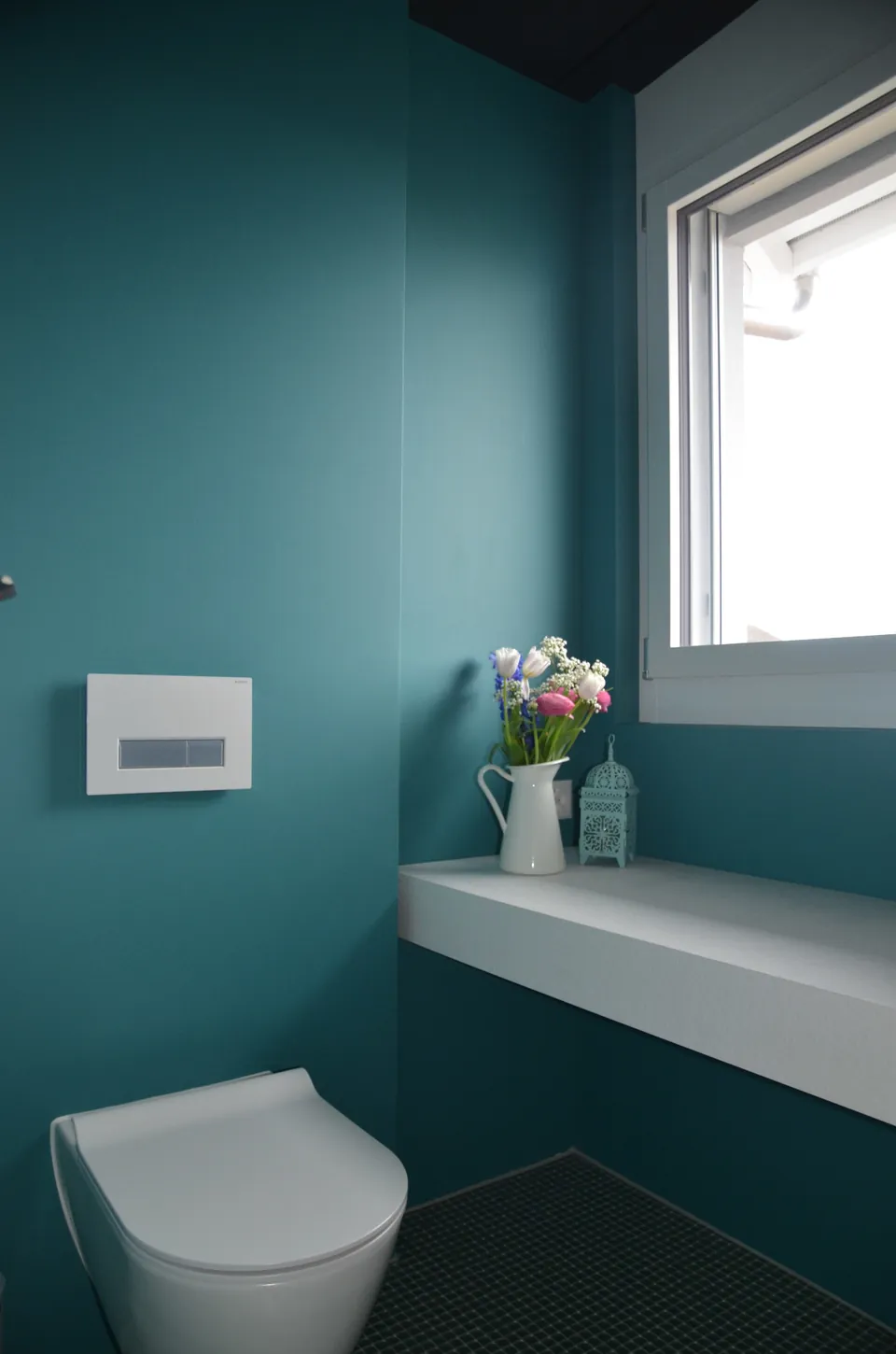 WC mit Wänden in kräftigem Petrol, weisser Ablage und Fenster