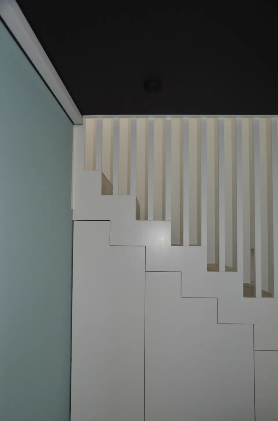 Treppe mit weissen Lamellen unter dunkler Decke
