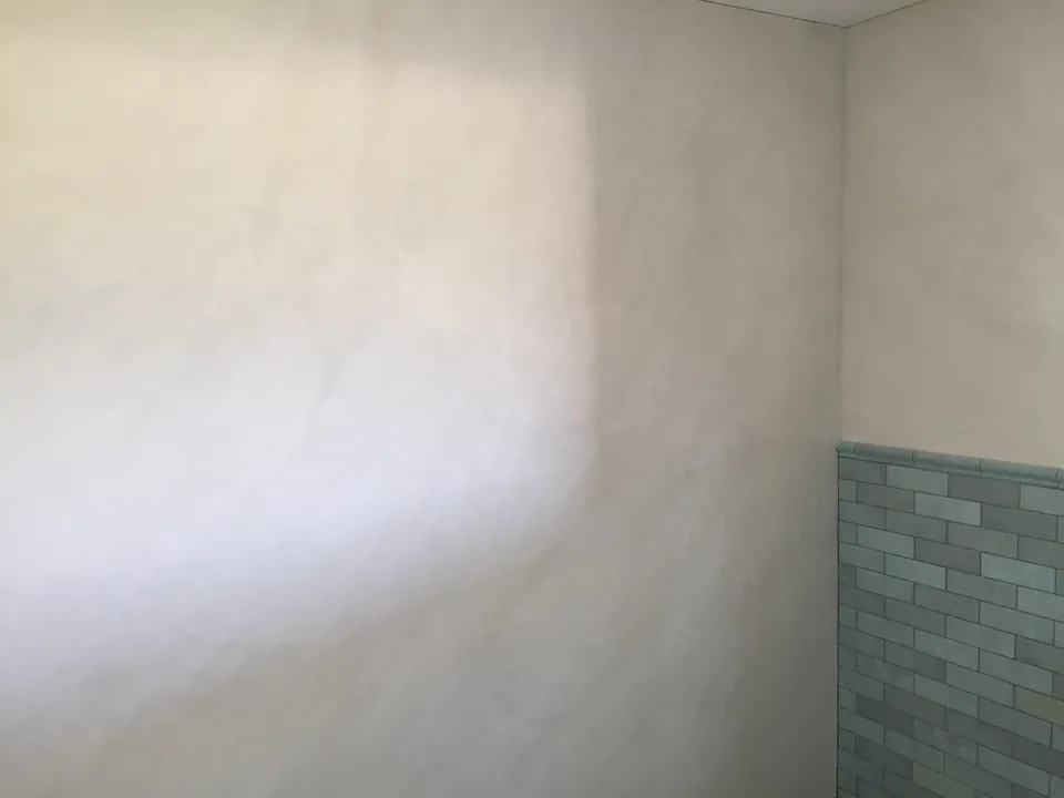 Helle fugenlose Wand neben grünen Wandfliesen