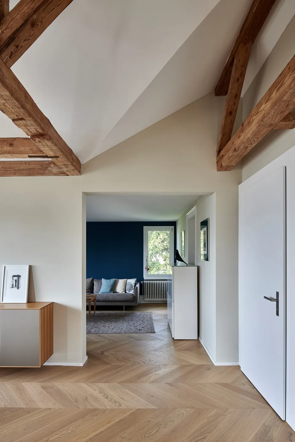 Dachgeschoss mit Holzbalken und Durchblick auf eine dunkelblaue Wand