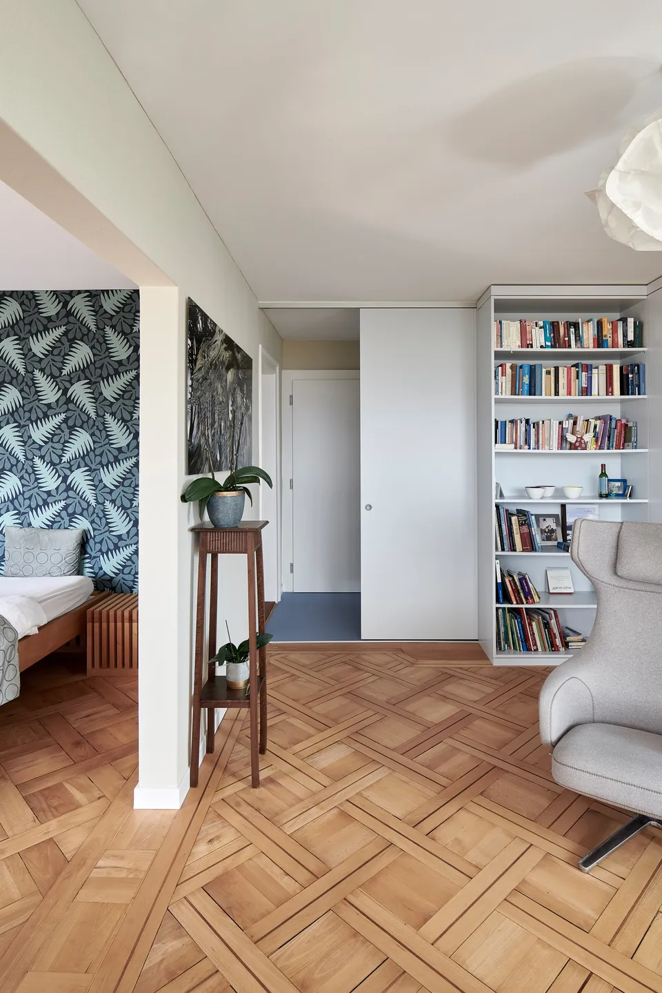 Zimmer mit Pflanzentapete, Parkett und Bücherregal