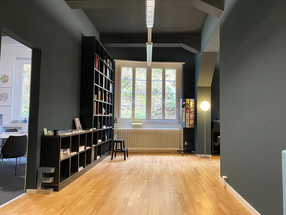 Raum mit dunkelgrüner Wand, Bücherregal und Holzboden