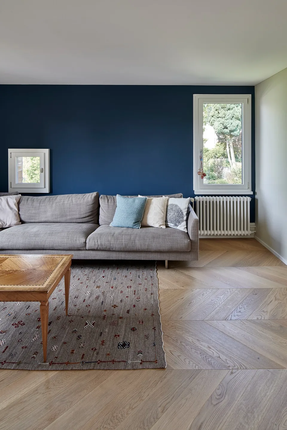Wohnzimmer mit dunkelblauer Wand, Sofa und Fischgratparkett