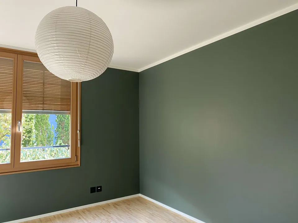 Leeres Zimmer mit graugrünen Wänden und Holzfenster