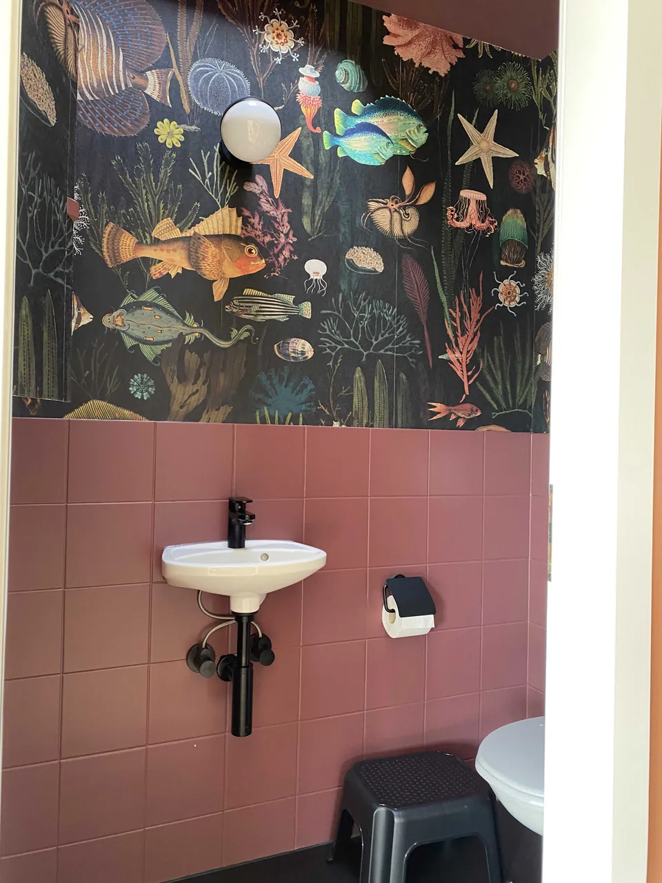 WC mit rosa Fliesen und Tapete mit Unterwassermotiv
