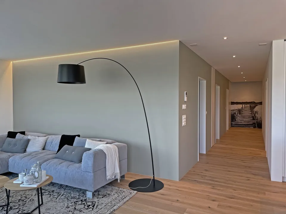 Wohnzimmer mit Bogenleuchte und hellen, warmgrauen Wänden
