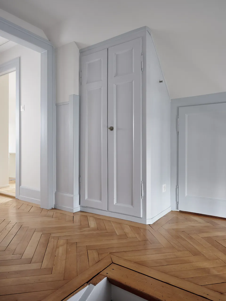 Korridor mit Fischgratparkett und Einbauschrank in Hellgrau