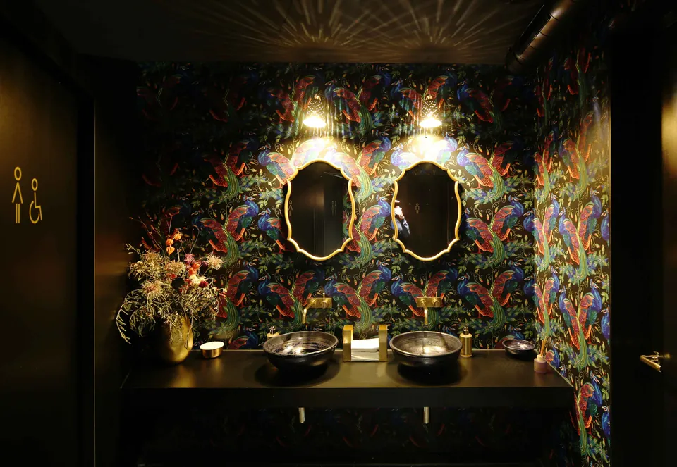 WC im Restaurant Majorelle mit farbiger Dschungeltapete und zwei ovalen Spiegeln