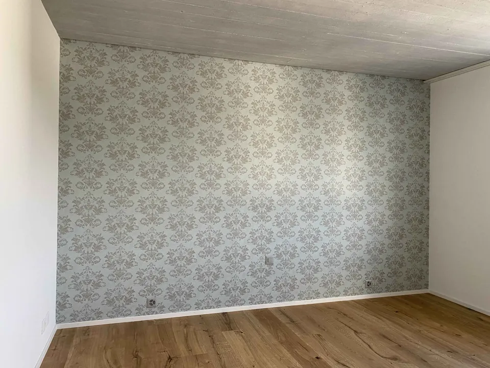 Zimmer mit hellgrüner, fein gemusterter Tapete und Eichenparkett