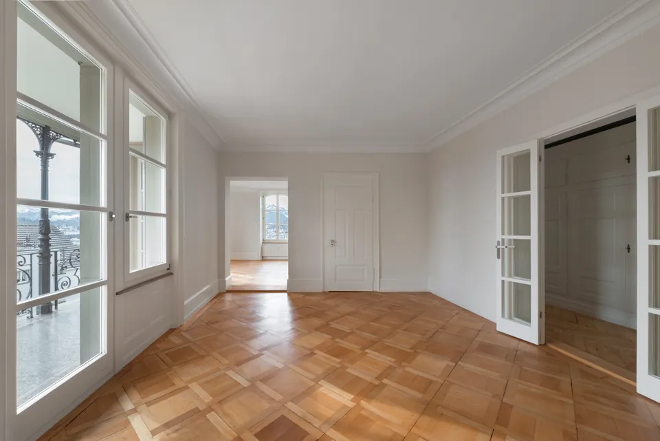 Zimmer mit Parkett und Balkontüren mit Blick ins Grüne