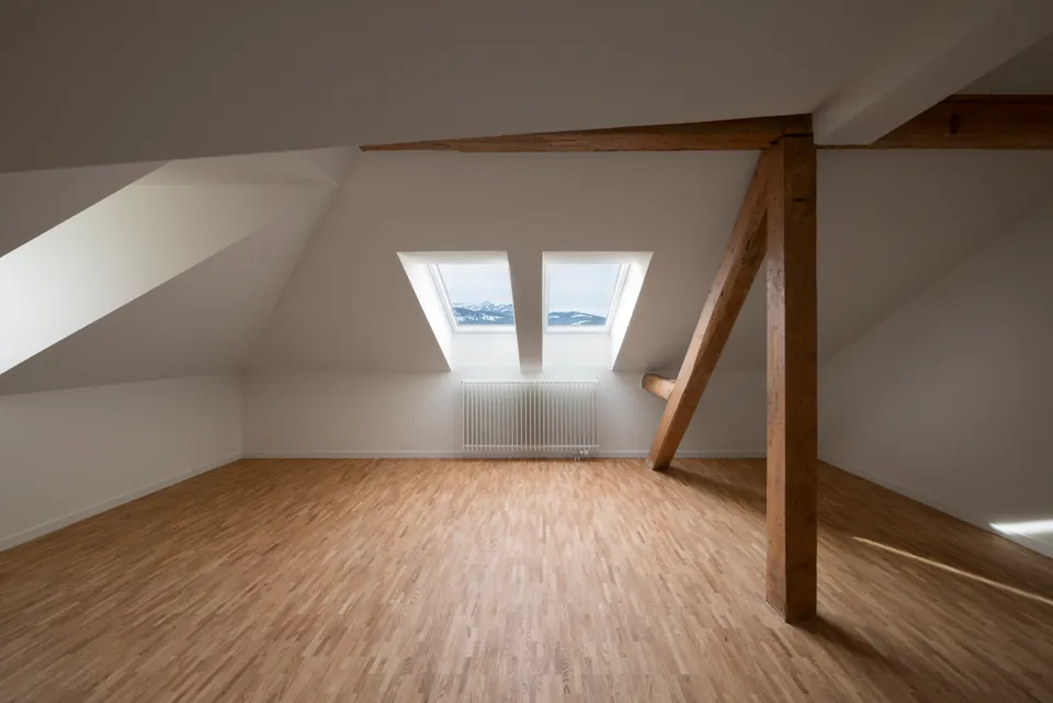 Dachzimmer mit Holzbalken und Dachfenstern