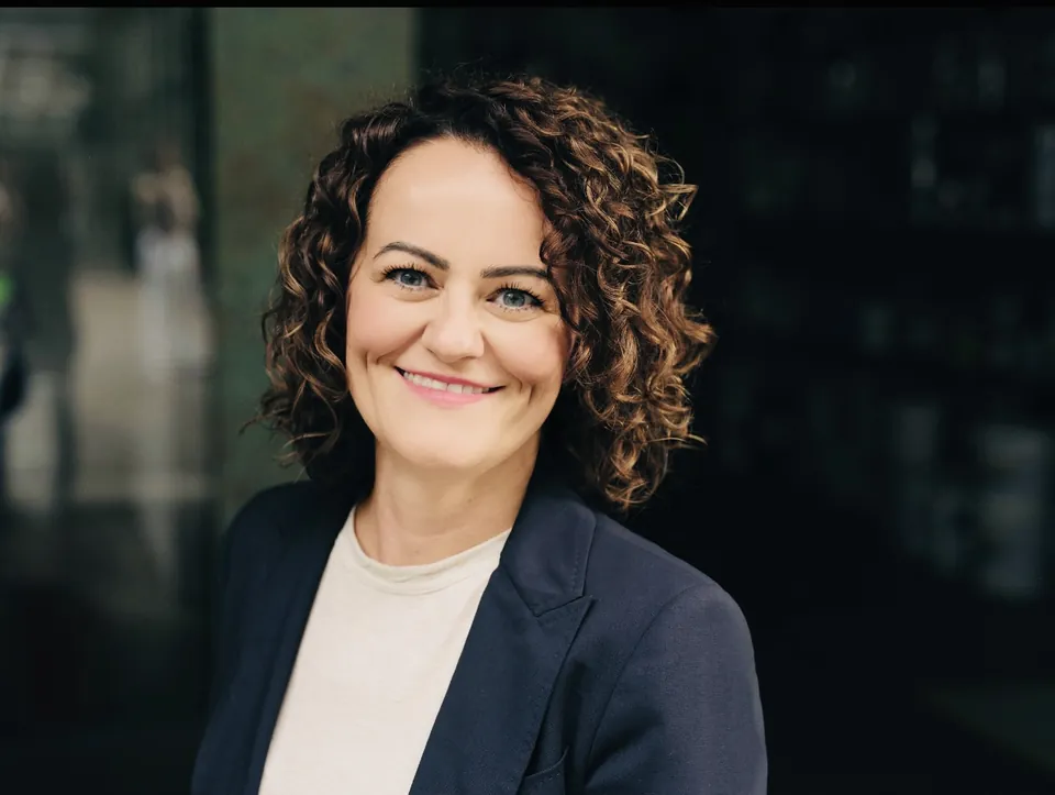 Meli Sabotic im dunklen Blazer vor dunklem Hintergrund